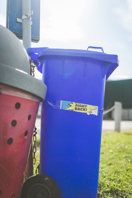A close-up image showing a pile of crushed aluminum and plastic soft drink cans, primarily in silver, red, blue, and yellow colors. The cans have visible pull-tabs, some with crumpled and dented surfa